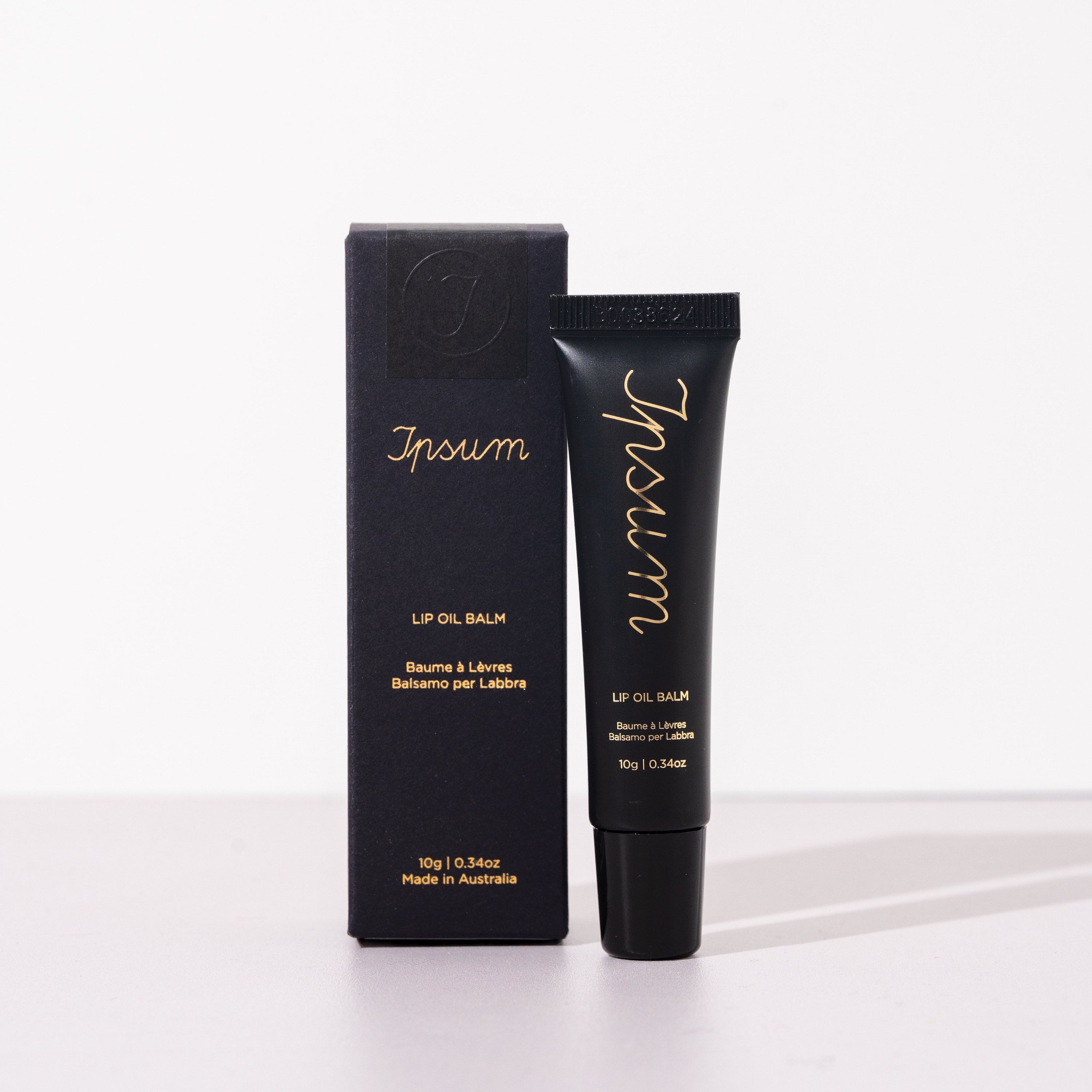Schwarze Ipsum Lip Oil Balm Tube und Verpackung vor weißem Hintergrund.