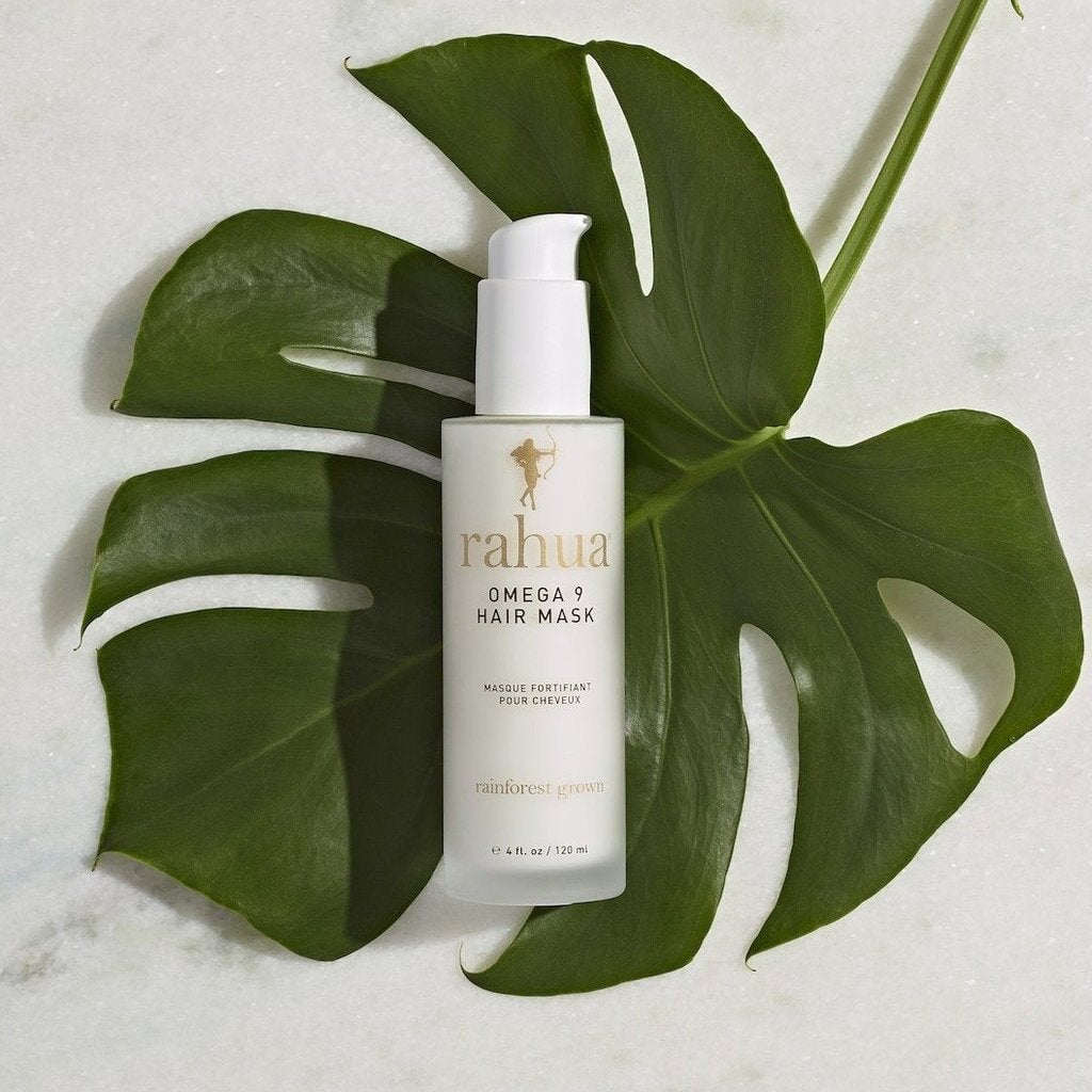 Rahua Omega 9 Hair Mask Flasche liegt in einem Palmenblatt.