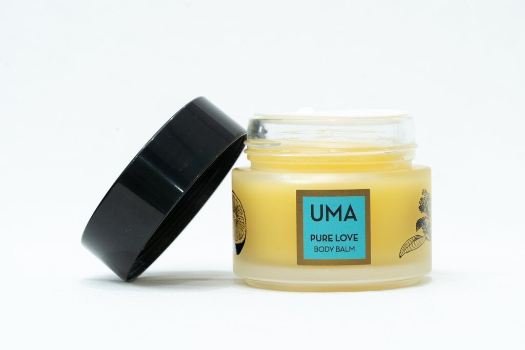 Schraubglas UMA Pure Love Body Balm mit offenem, schräg an das Glas angelehnten schwarzem Deckel steht vor weißem Hintergrund. North Glow