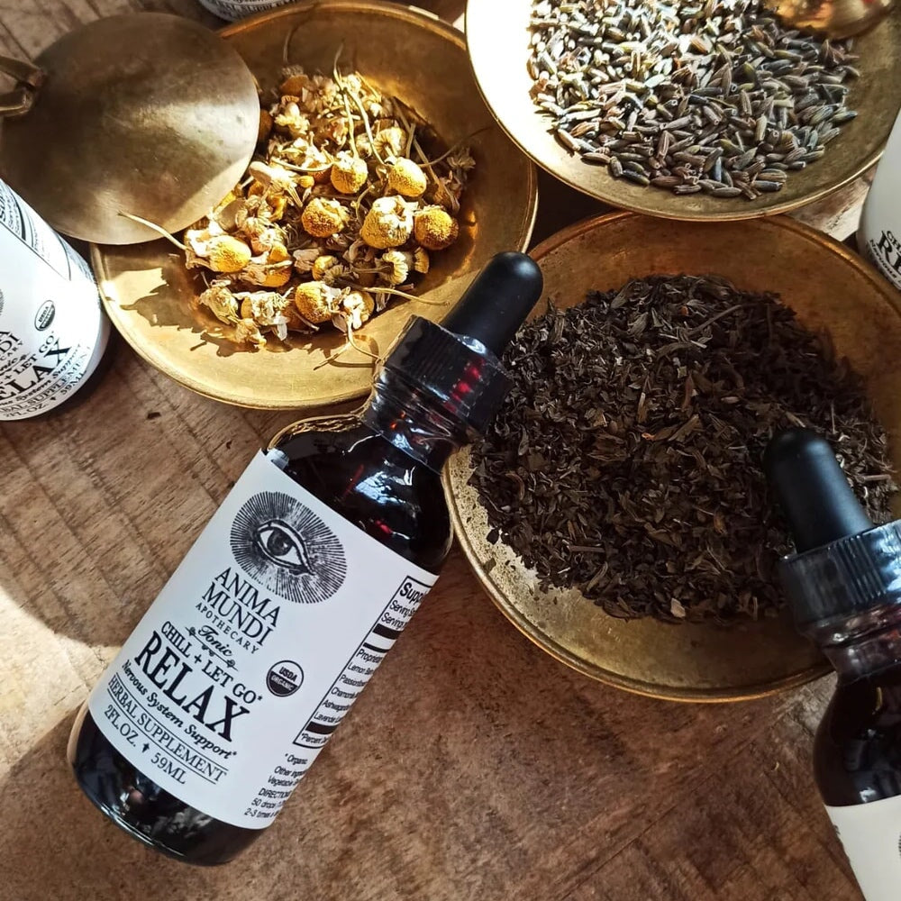 Anima Mundi Relax Pipettenflasche aus der Vogelperspektive, liegt zwischen mit Kräutern befüllten Messingschalen.