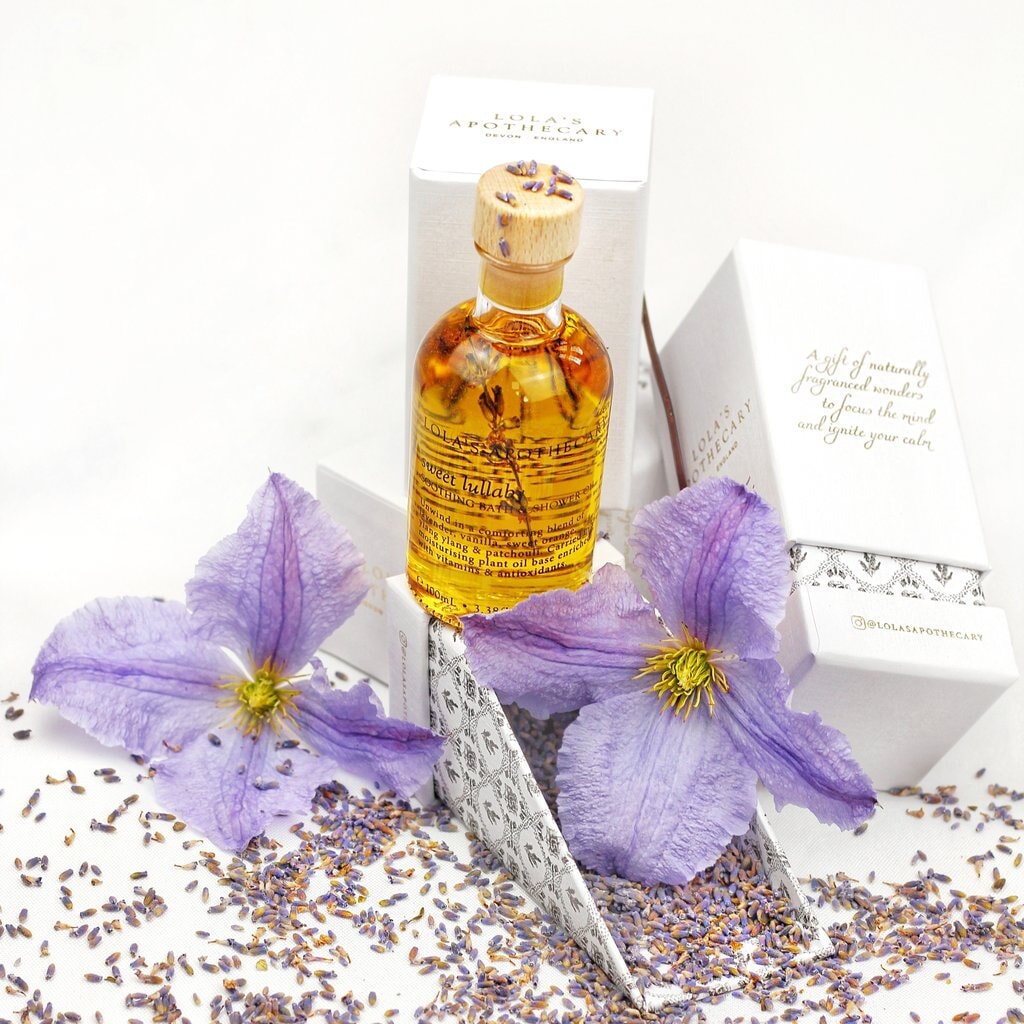 Lola's Apothecary Glasflasche mit Korken steht vor der Verpackung auf Lavendelblüten.