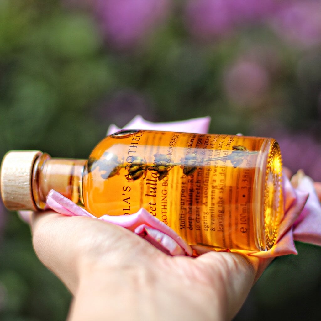 Glasflasche Lola´s Apothecary mit orngefarbenem Inhalt liegend auf einer Hand.