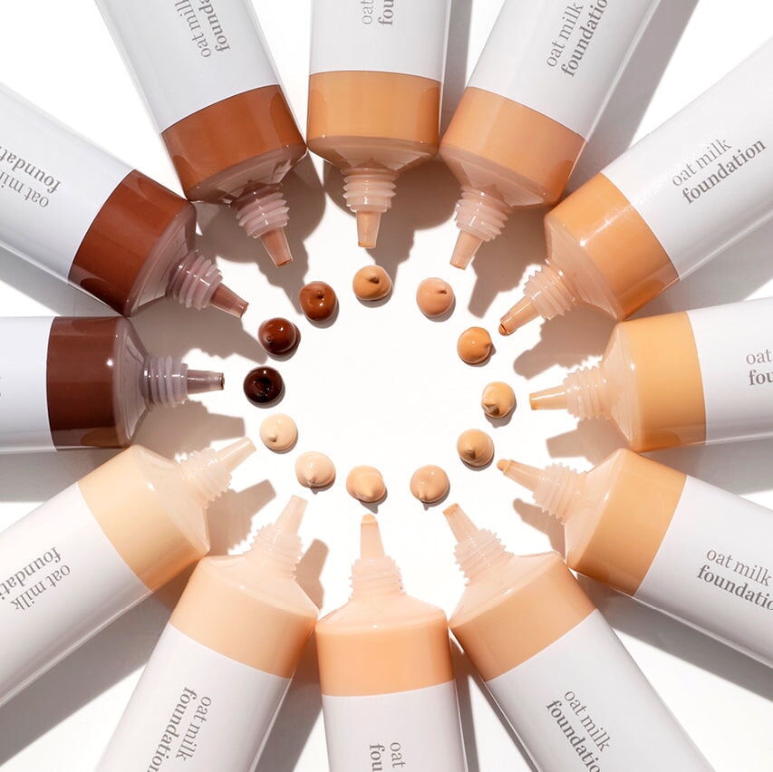 Ere Perez Oat Milk Foundations liegen im Kreis in der Mitte jeweils verschiedene Farbbeispieltupfer.