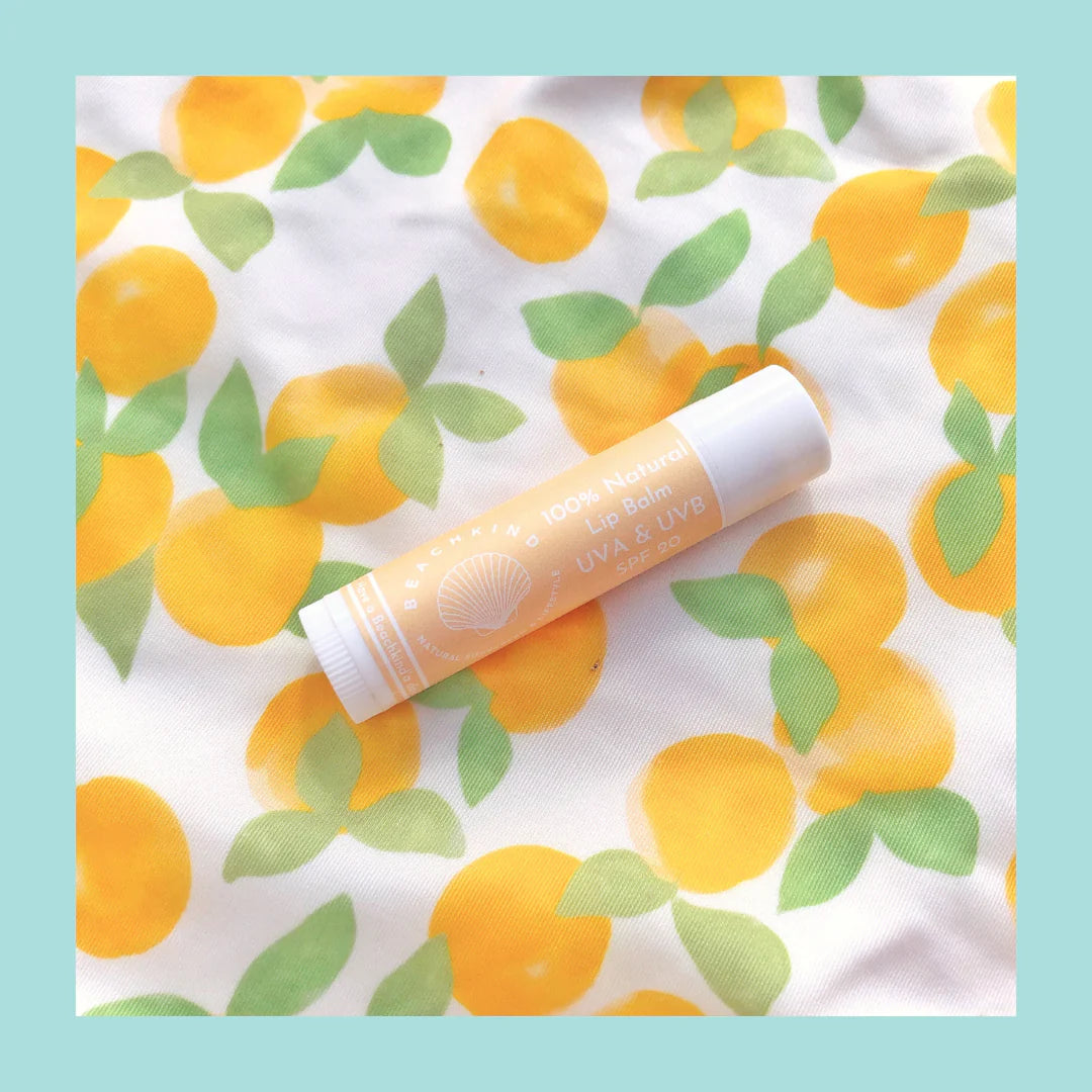 Natural Lip balm von Beachkind liegend auf einer Decke, wo Orangen abgebildet sind. North Glow