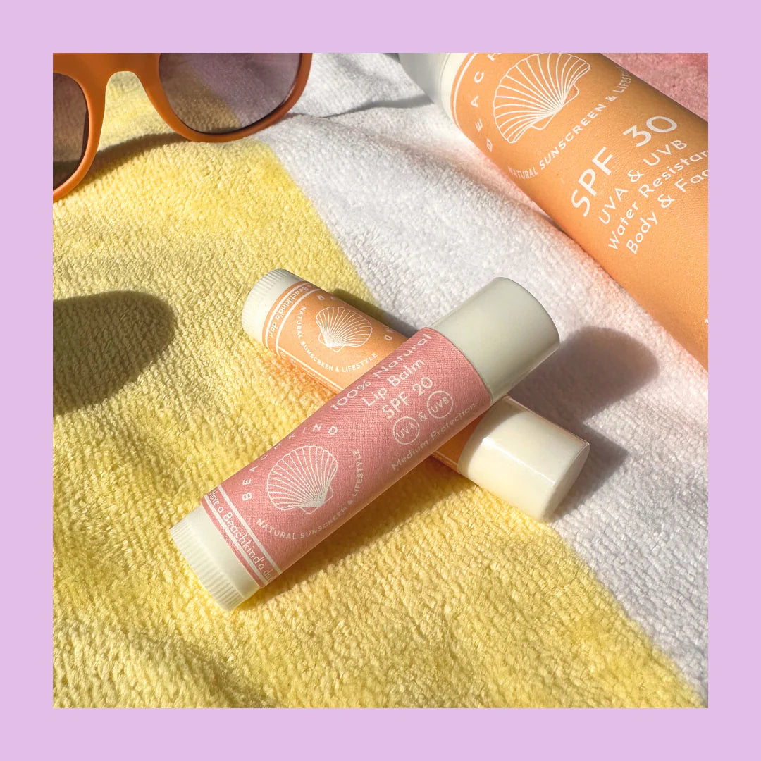 Zwei Beachkind Lip Balms liegend aufeinander, auf einem gelb-weißen Handtuch.