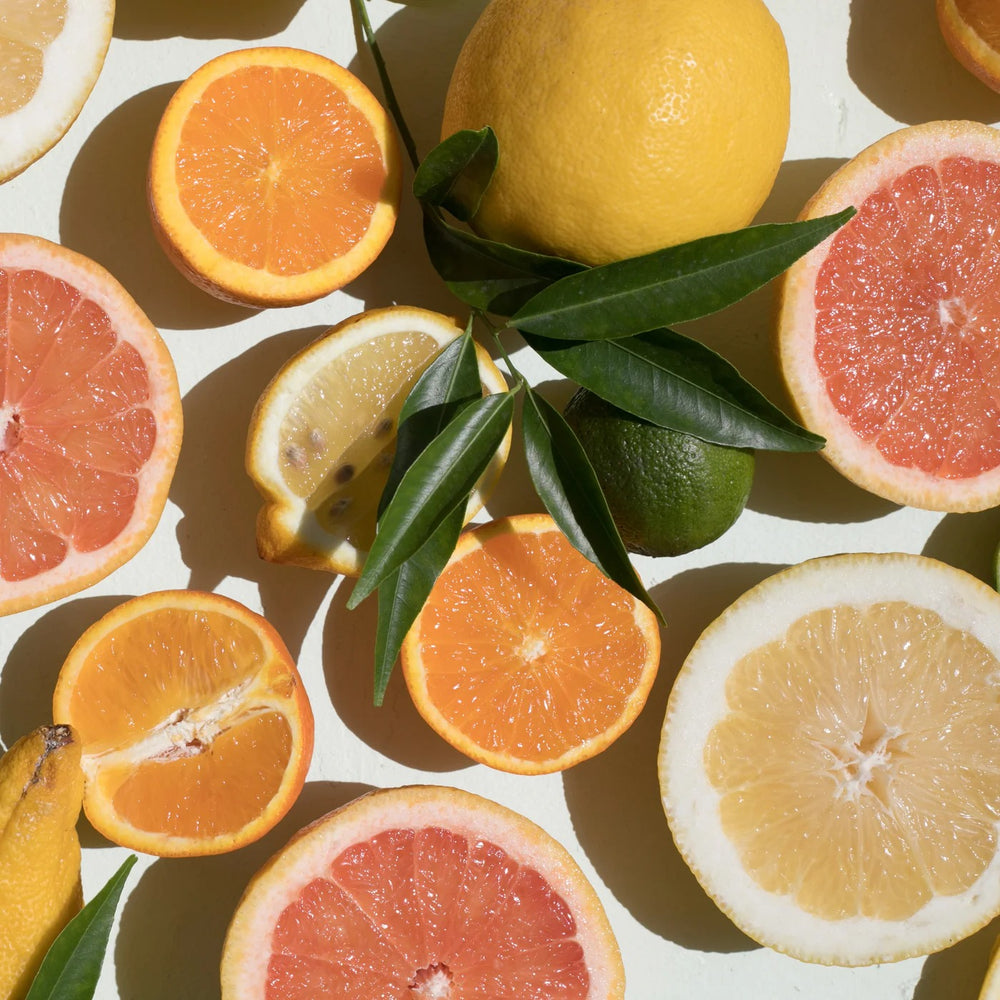Aufgeschnittene Zirusfrüchte wie Orange, Mandarine, Blutorange und Limette liege auf weißem Untergrund aus der Vogelperspektive sichtbar. 