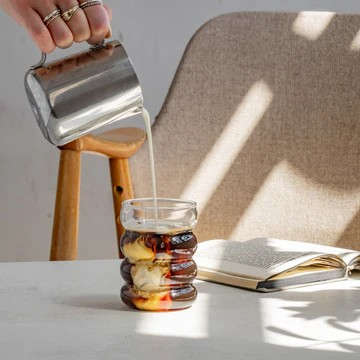 In ein mi Kaffee befülltes Bubble Glas Blanko von Eulenschnitt wird Milch hineingegossen.