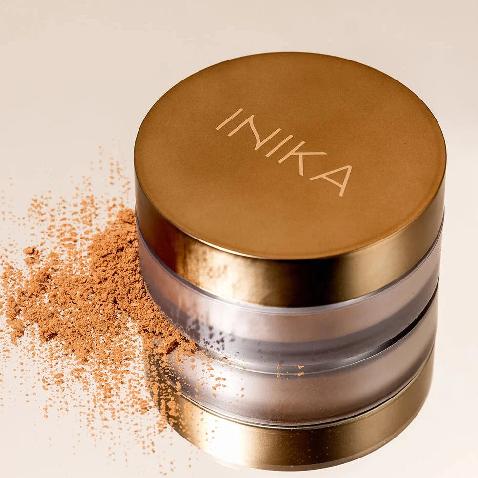 INIKA Loose Mineral Bronzer in milchigem Glas mit kuperfarbenen Deckel auf beigem Hintergrund