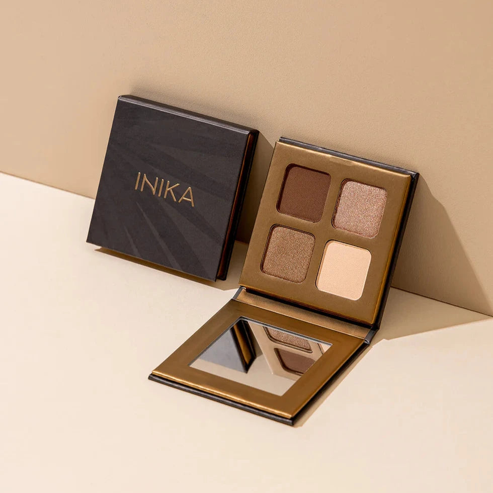 2 INIKA Organic Quad Eyeshadow Paletten (Wind) nebeneinander, einer davon geöffnet, an einer Wand gelehnt. North Glow