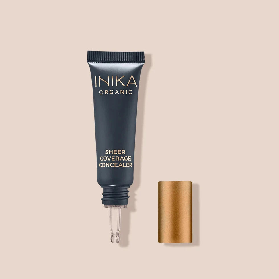 INIKA Sheer Coverage Concealer in schwarzer Tube mit kupferfarbenen Verschlusss vor beigem Hintergrund North Glow