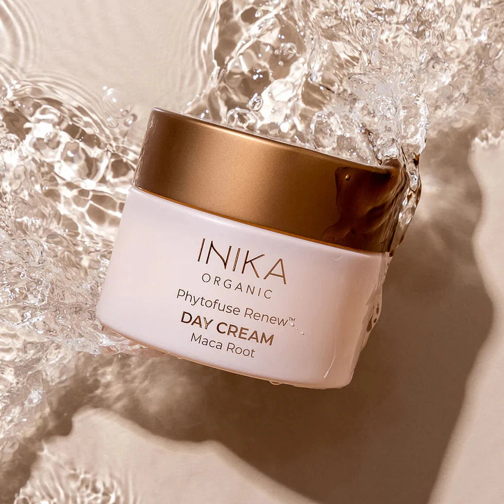 INIKA Phytofuse Renew Day Cream in rosa milchigem Tiegl mit bronzefarbenen Deckel und Aufschrift, umgeben von Wasser in Bewegung. North Glow