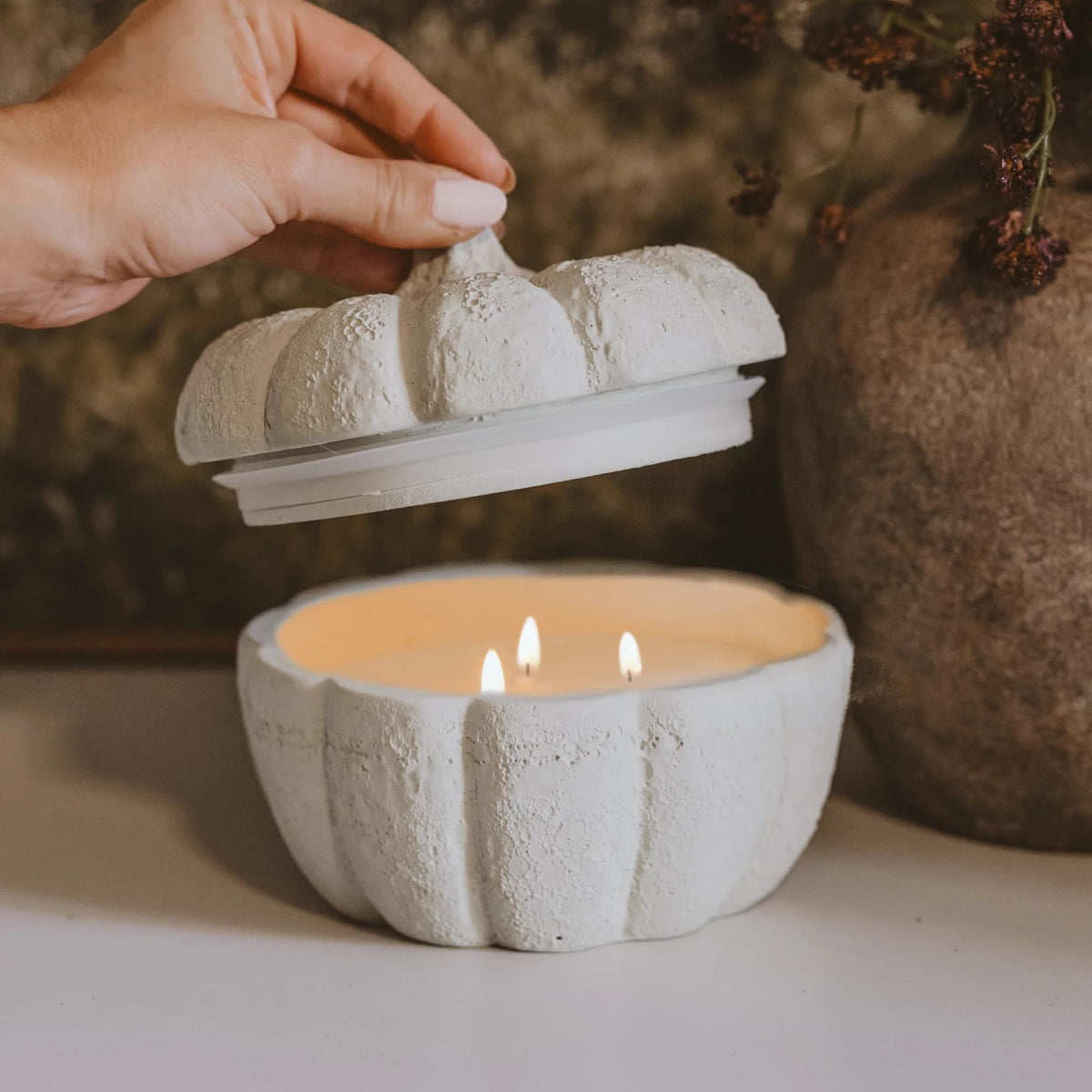 Sweet Water Decor Cashmere and Vanilla Kerze in Kürbisgefäß mit drei brennenden Dochten, geöffneter Deckel.