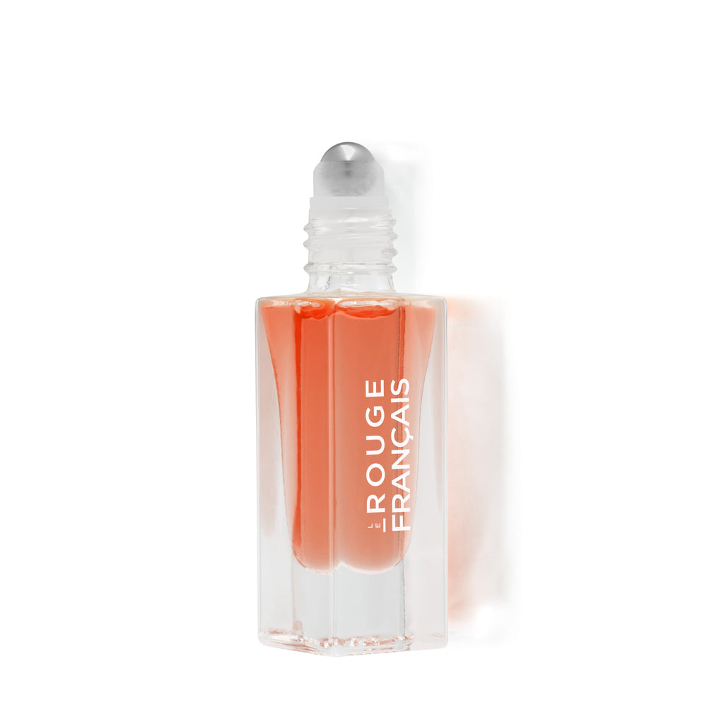 Lippenöl in einer Glasflasche ohne Deckel mit Kugel Aplikator von Le Rouge Francais vor weißem Hintergrund. 