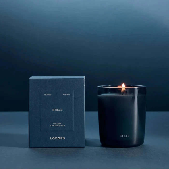 Looops Stille Kerze in blau getöntem Glas, 75 g neben Produktverpackung.