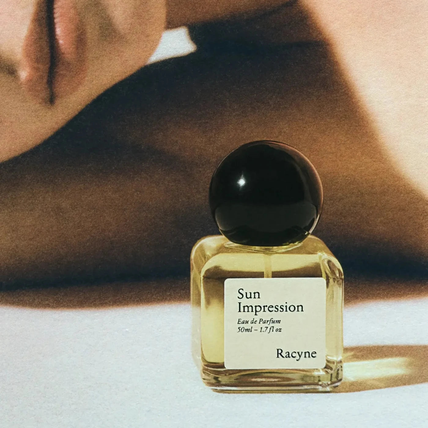 Sun Impression Eau de Parfum Flakon von Racyne, im Hintergrund weiblicher Körper.