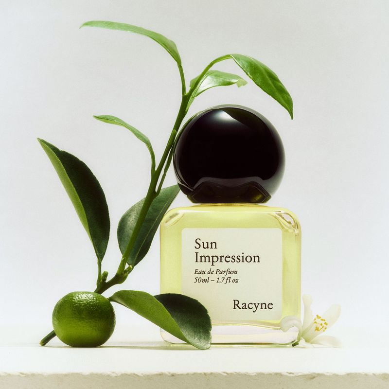 Sun Impression Eau de Parfum Flakon, daneben eine Pflanze von Racyne