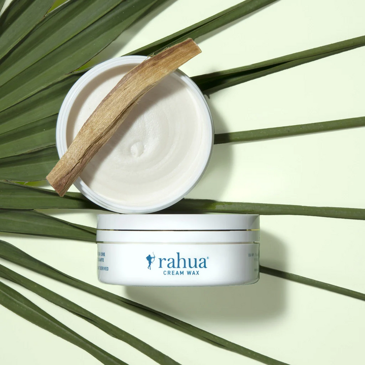 offene Rahua Cream Wax Dose auf einem Palmenblatt vor hellgrünem Hintergrund.