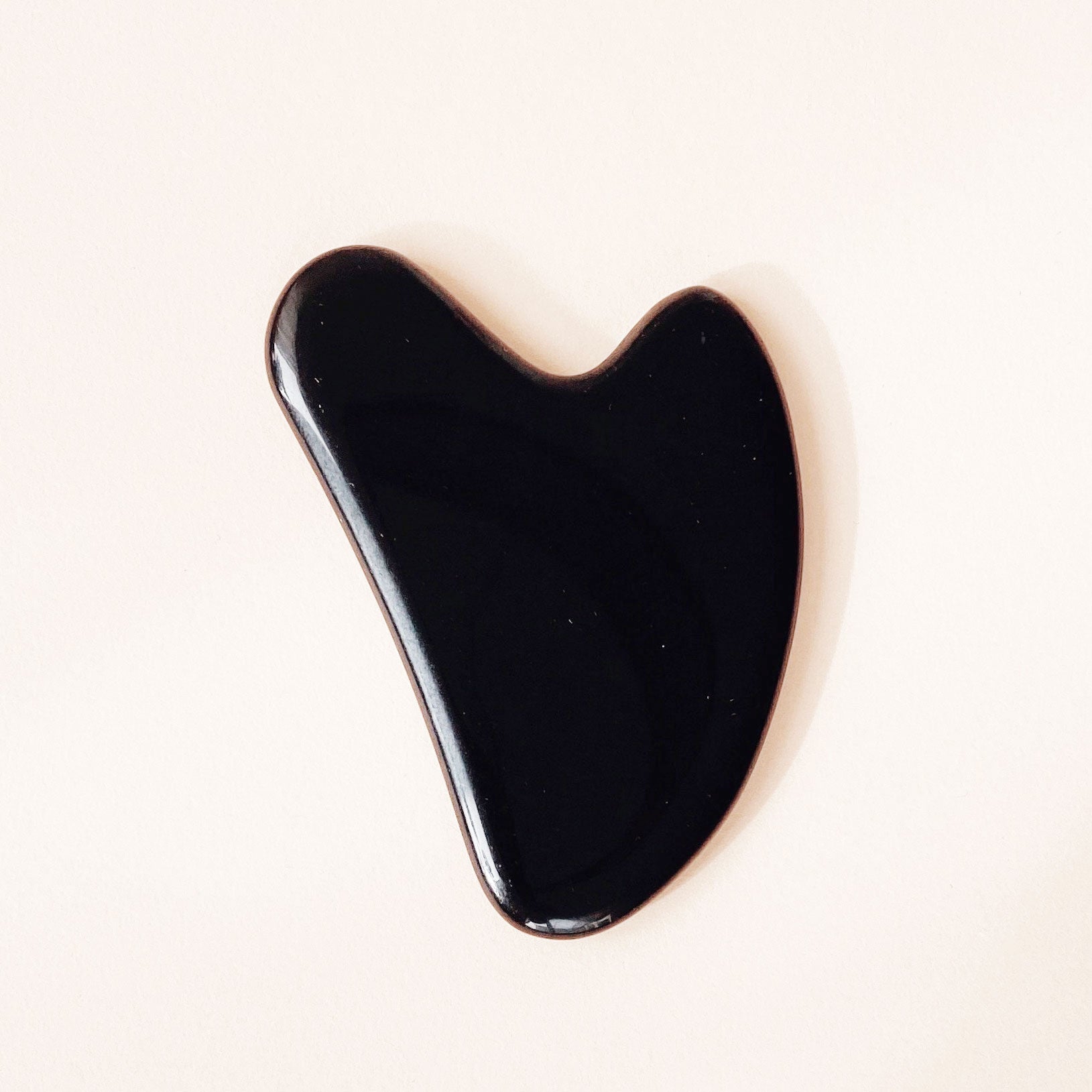 Ruhi The Obsidian Gua Sha vor beigem Hintergrund 