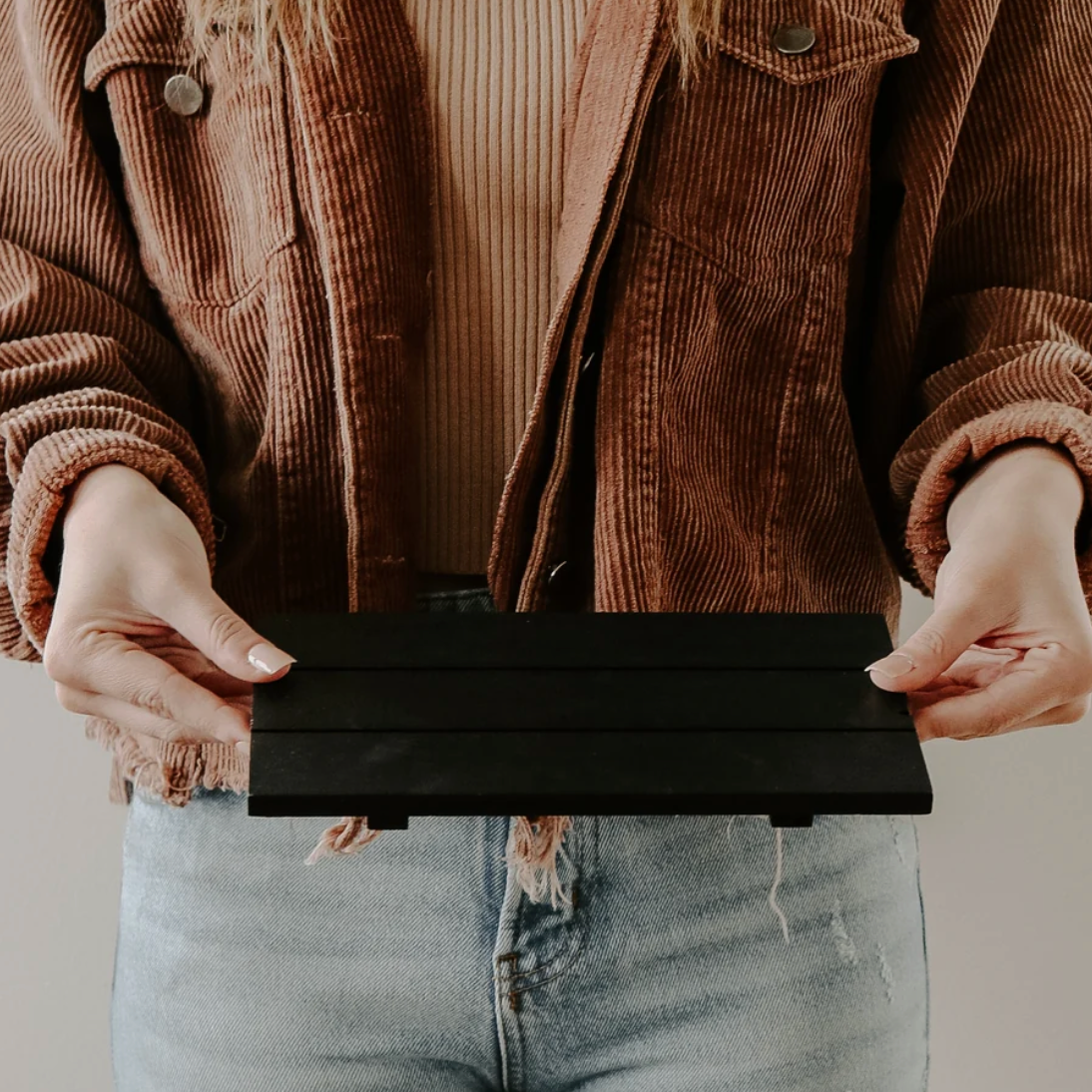 Sweet Water Decor Black Wood Tray wird in die Kamera gehalte