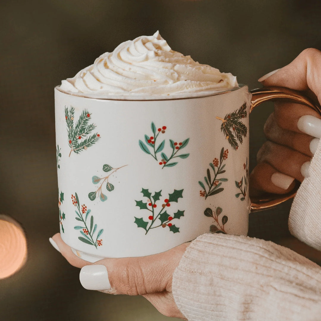 Weihnachtliche Tasse "Holiday Greenery" von Sweet Water Decor wir von zwei Händen gehalten.