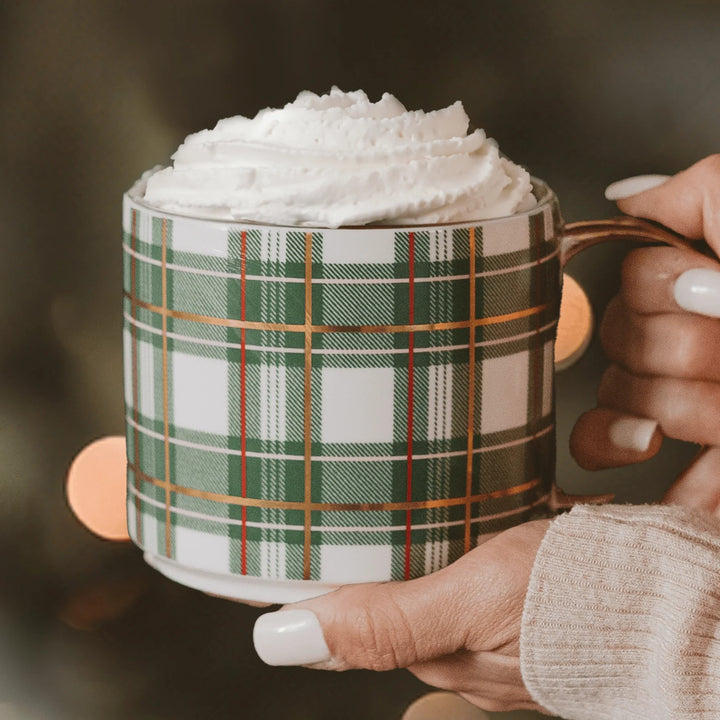 Sweet Water Decor Tasse Green Plaid mit Sahnehaube wird von 2 Händen gehalten.