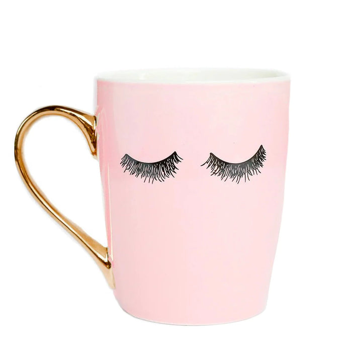 Rosafarbene Kaffeetasse "Pink Eyelashes" mit Wimpernaufdruck und goldenem Henkel vor weißem Hintergund