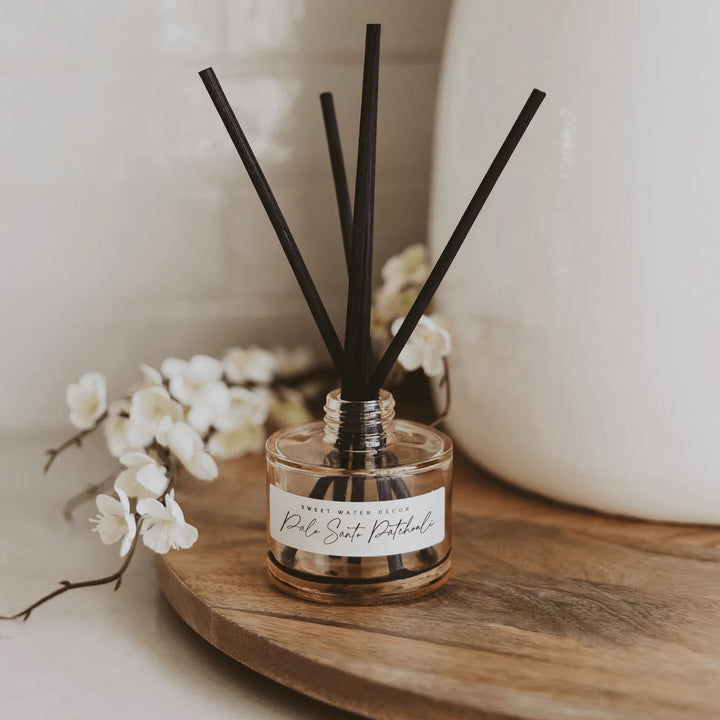 Diffuser Palo Santo Patouchli Tinted Glass Jar mit Duftstäbchen steht auf einem Holztisch.