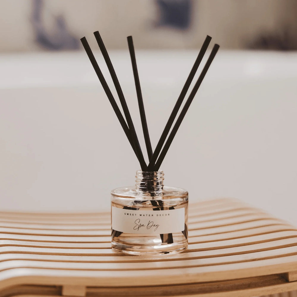 Diffuser Spa Day Tinted Glass Jar mit Duftstäbchen steht auf einem Holztisch.