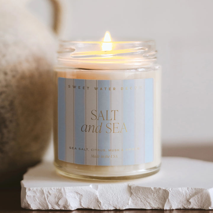 Brennende Sweet Water Decor Duftkerze Salt and Sea im durchsichtigem Glas mit gestreiften Etikett.
