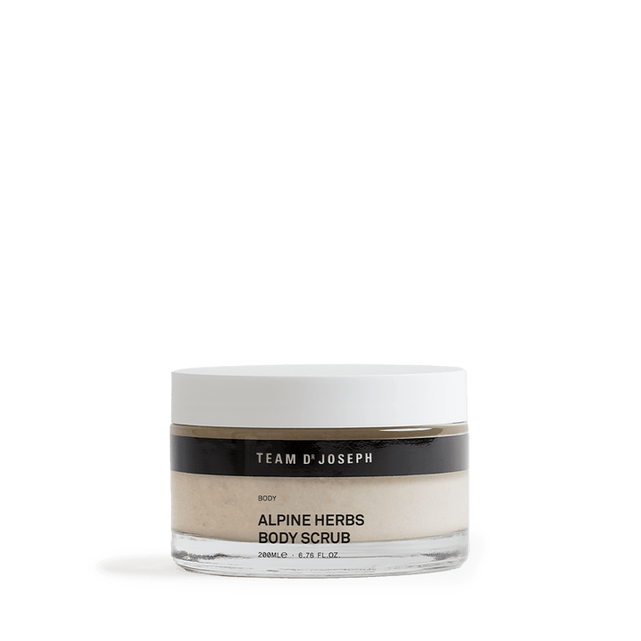 Team Dr Joseph Alpine Herbs Body Scrub – eleganter Glastiegel mit weißem Deckel und schwarzem Etikett, naturfarbenes Körperpeeling sichtbar durch das transparente Glas.
