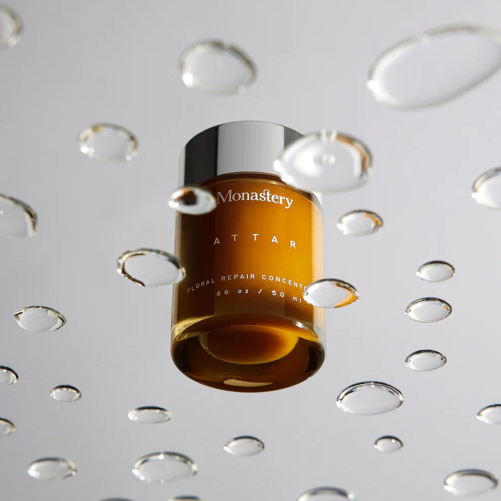 Monastery Attar Balm Konzentrat 50ml Tiegel durch transparenter Scheibe mit Wassertropfen fotografiert. North Glow