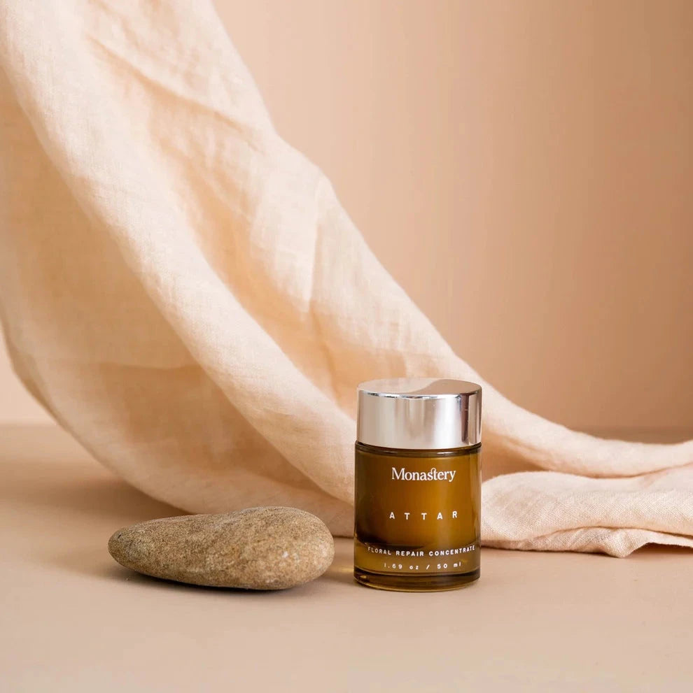 Vor drappiertem Leinentuch liegt ein Stein und der Monastery Gold Balm Konzentrat 50ml Tiegel.