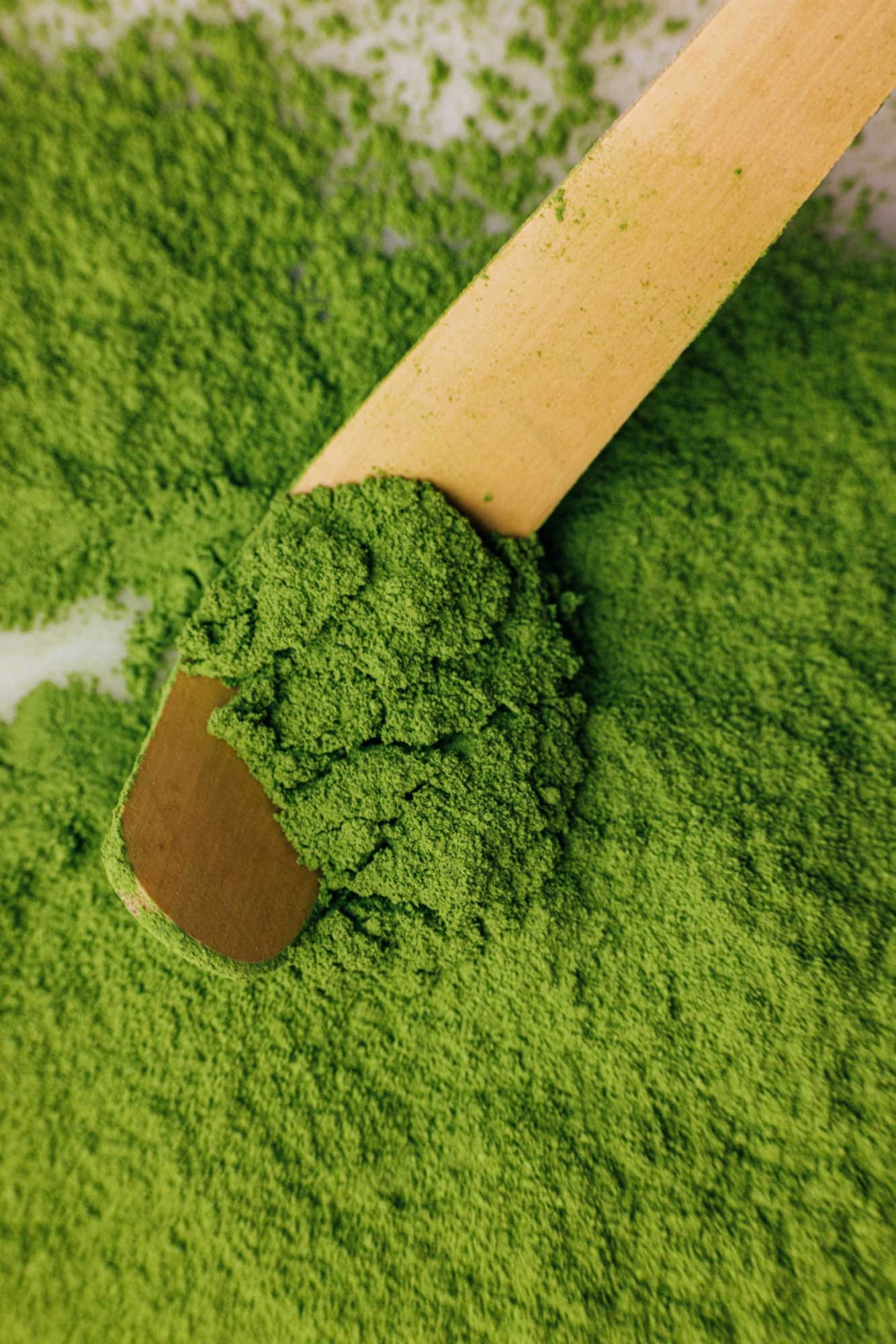 Grünes Matchapulver mit Holzlöffel.