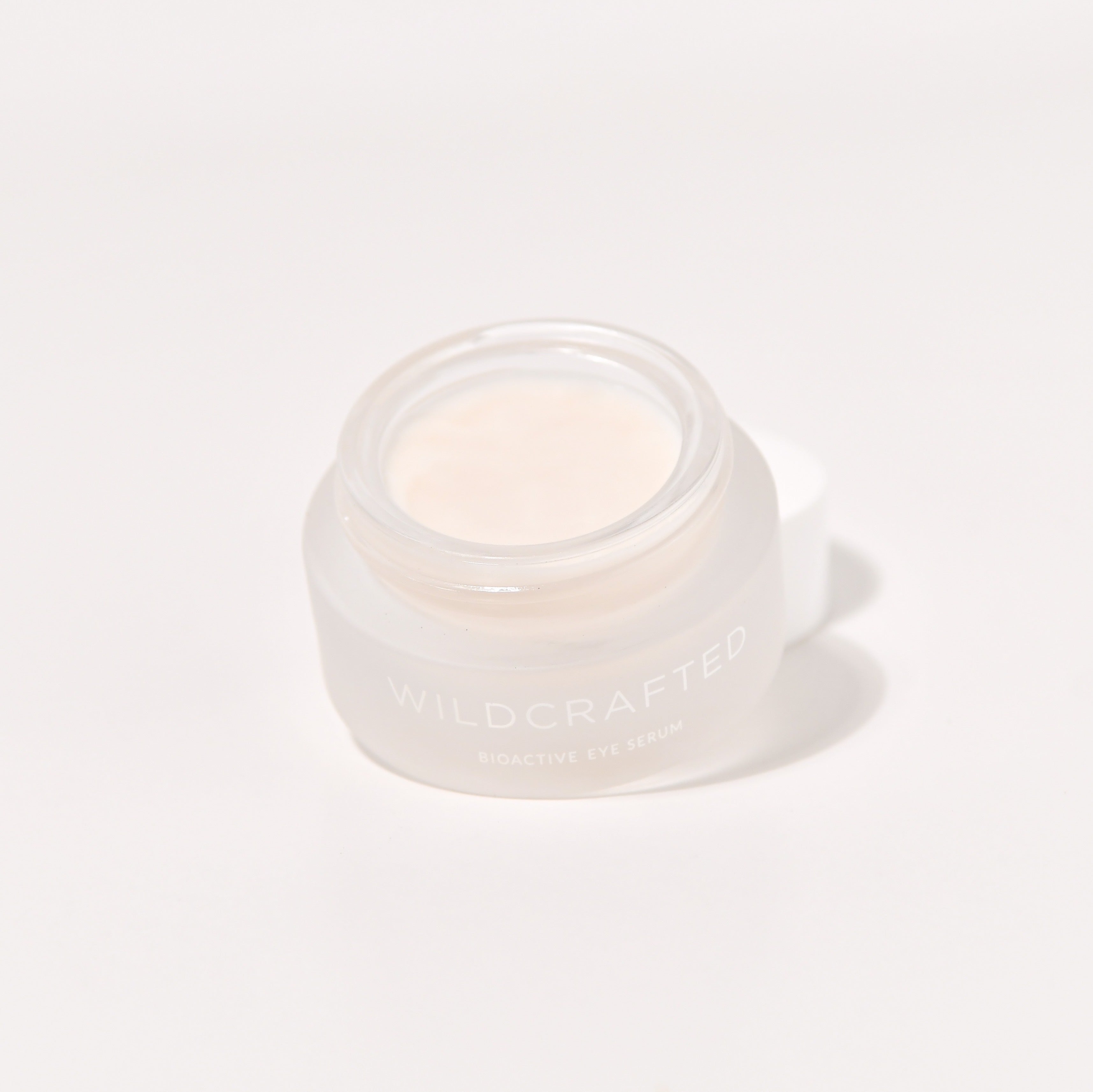 Offener Milchglastiegel Wildcrafted Bioactive Eye Serum vor weißem Hintergrund.