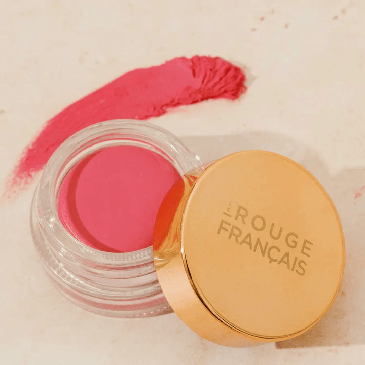 Cheek & Lip Zénobie Glastiegel mit offenem, goldenem Deckel steht neben einem Textur- und Farbbeispielauf weißem Untergrund.