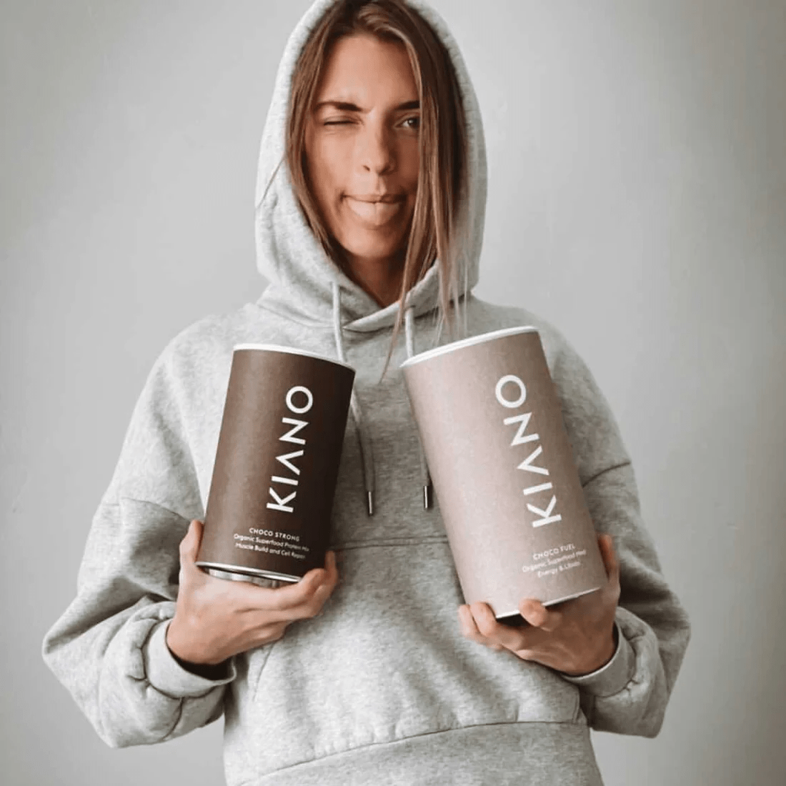 Frau mit Hoodie hält 2 Kiano Choco Dosen in den Händen.