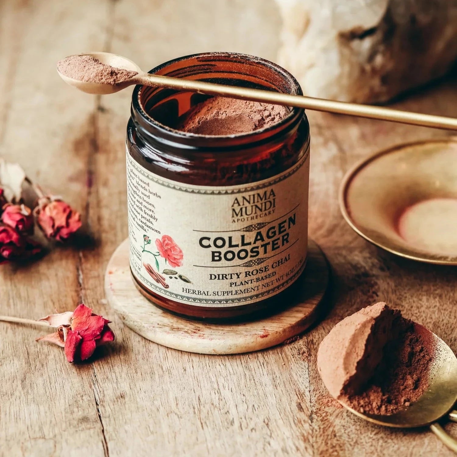 Offenes Anima Mundi Schraubglas Collagen Booster mit draufliegendem Messinglöffel befüllt mit Pulver.
