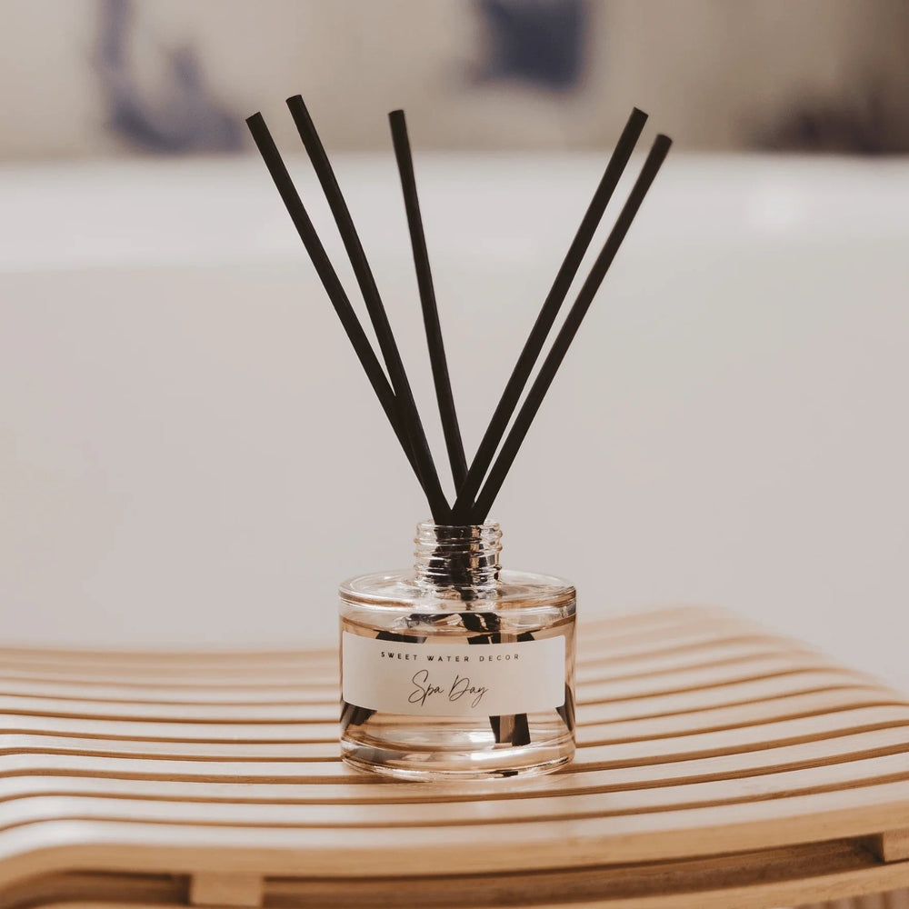 Diffuser Spa Day Tinted Glass Jar mit Duftstäbchen steht auf einem Holztisch.