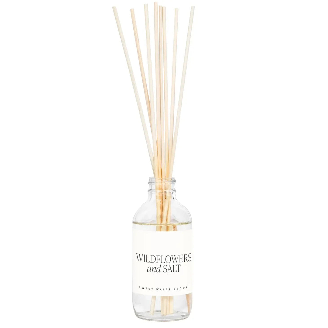 Transparente Flasche Diffuser Wildflowers and Salt von Sweet Water Decor mit Schilfrohrstangen, steht vor hellem Hintergrund. North Glow