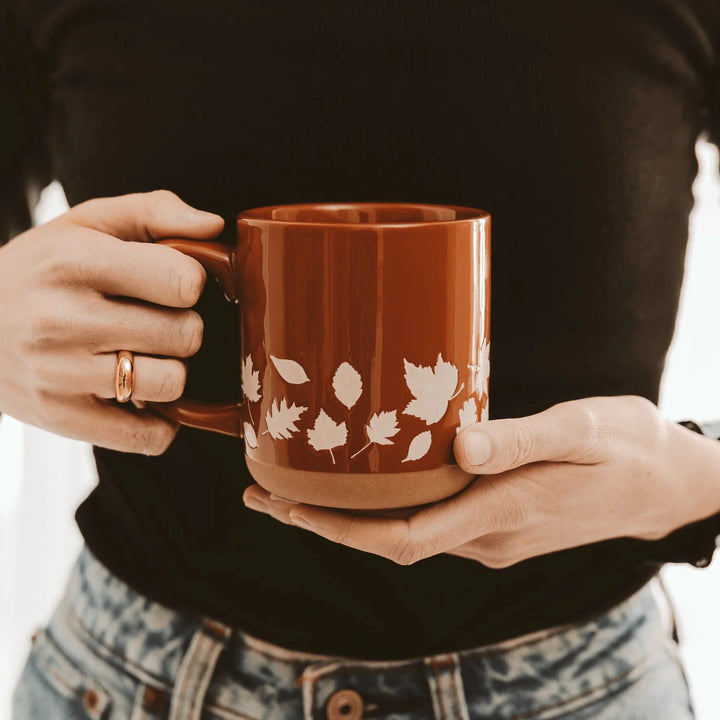 Fall Leaves orangene Kaffeetasse von Sweet Water Decor in Händen gehalten.