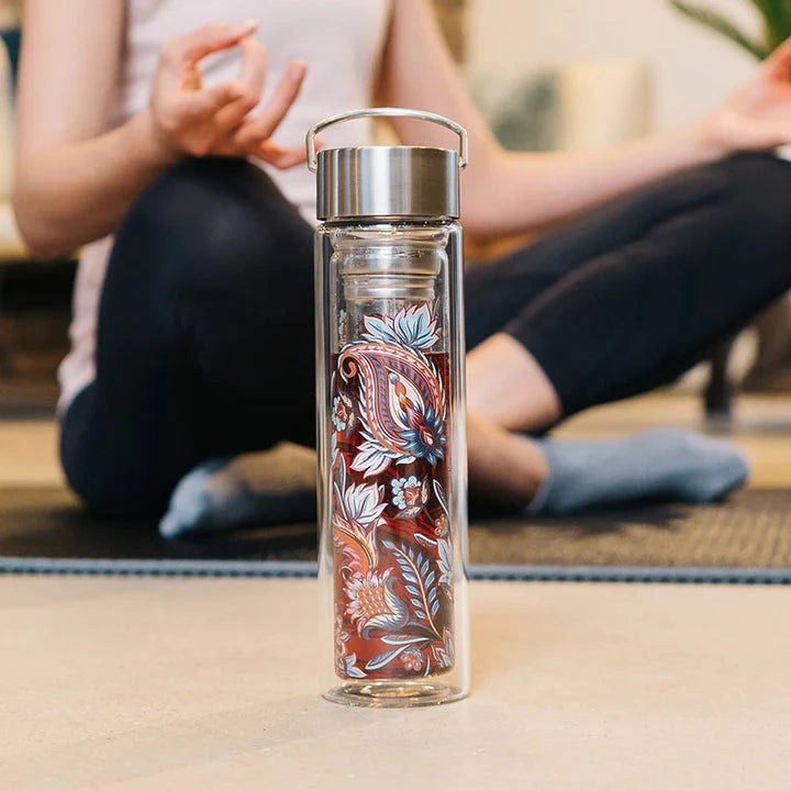 Flowtea Flache mit "Fireflower" Muster steht im Vordergrund, daginter eine meditierende Person