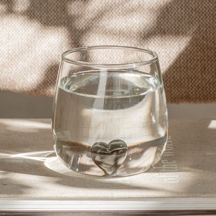 Bauchiges Trinkglas mit schwarzem Herz im Zentrum von Eulenschnitt gefüllt mit Wasser.