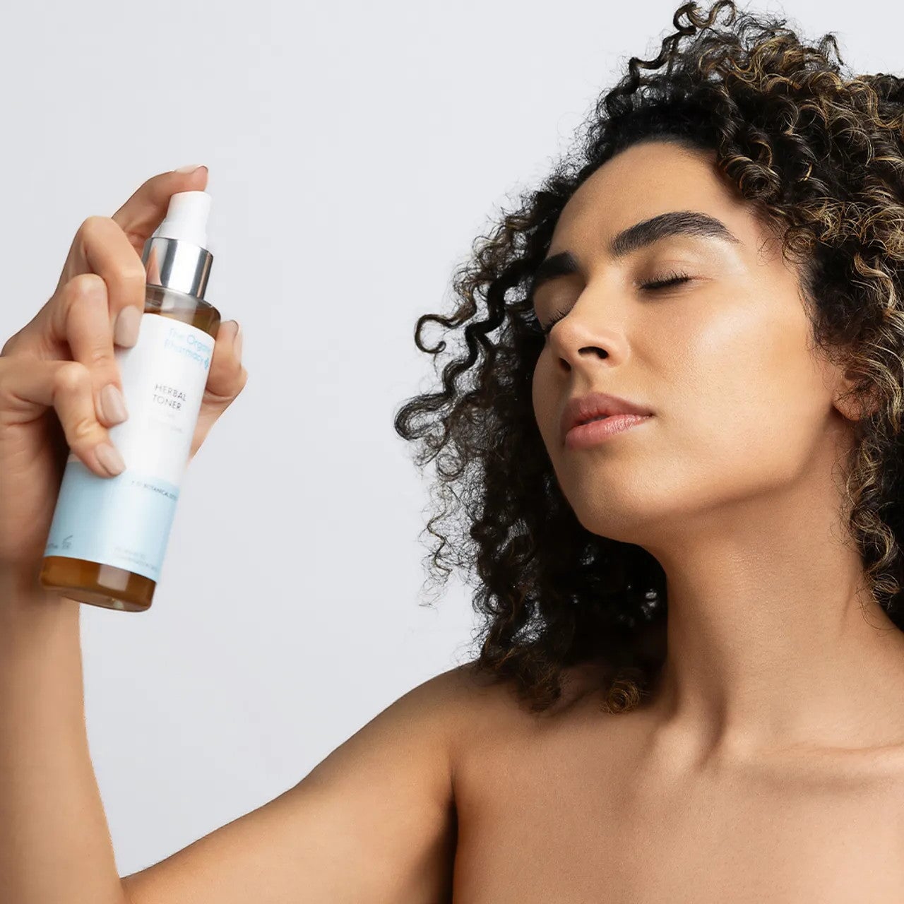 Eine Dame sprüht sich Herbal Toner von Organic Pharmacy ins Gesicht.