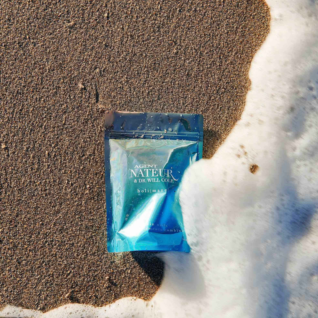  (mane) hair skin nails supplement Tüte aus der Vogelperspektive liegt am Strand umspielt  von Meerwasser. North Glow