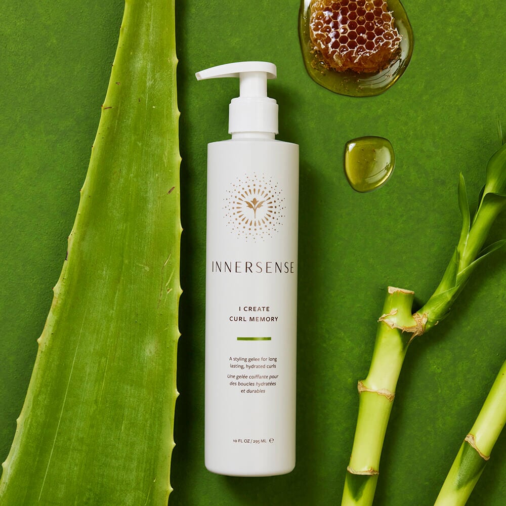 Innersense I Create Curl Memory Flasche auf grünem Hintergrund dekoriert mit Bambus, Aloe Vera und Honigwaben.