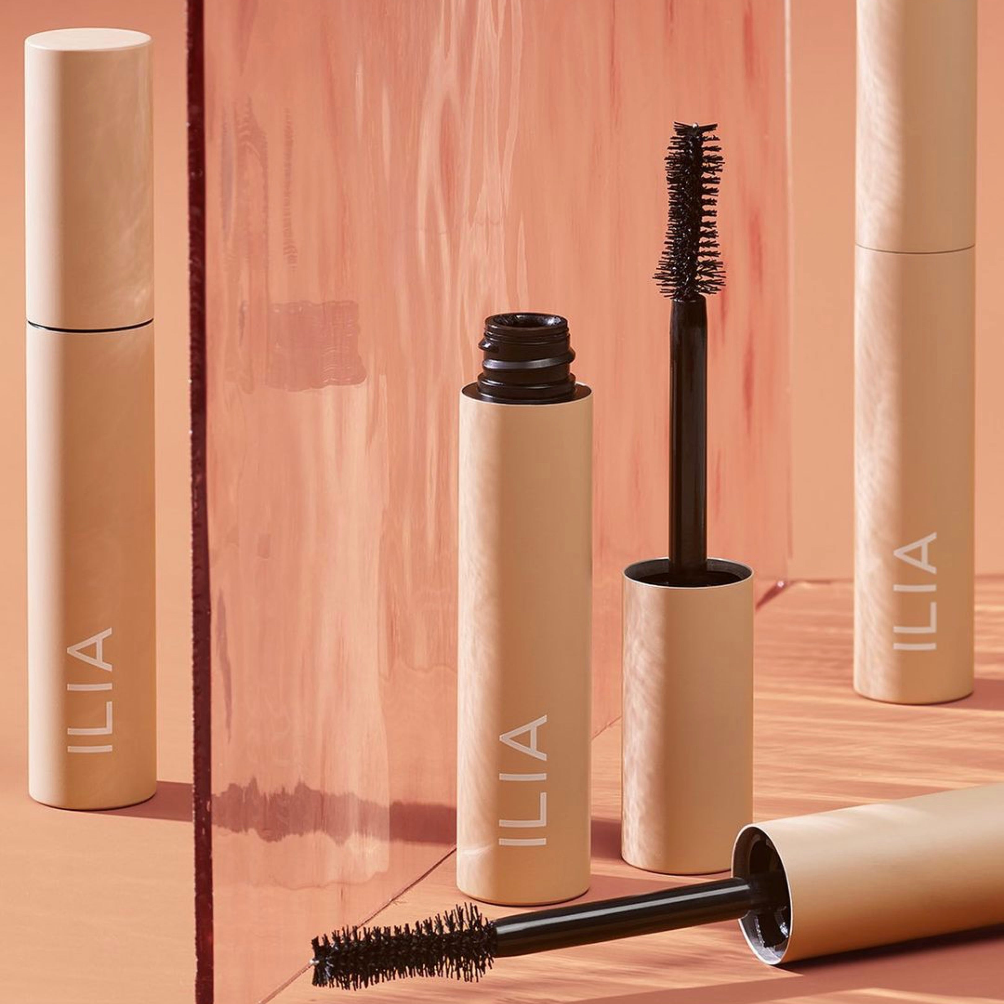 Mehrere Fullest Voluminizing Mascara von Ilia stehen teils geöffnet, teils geschlossen nebeneinander.