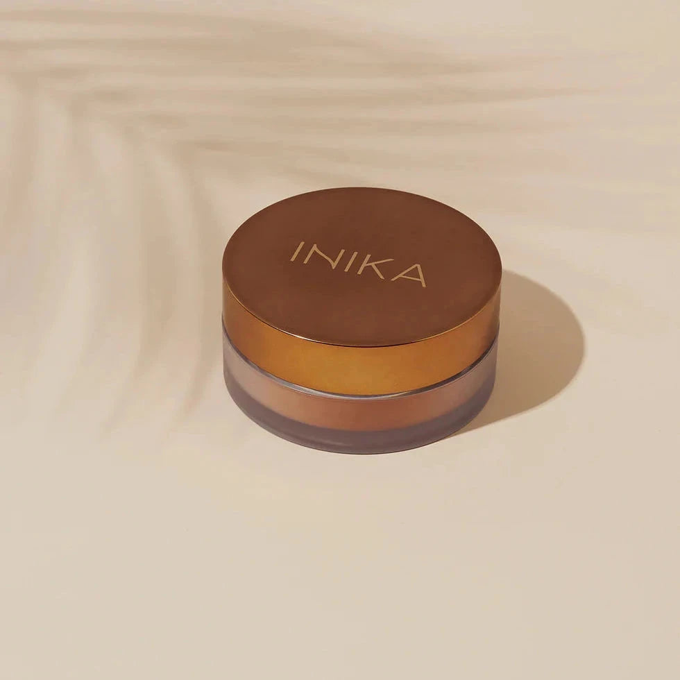 INIKA Loose Powder Bronzer Verpackung auf beigem hitergrund North Glow