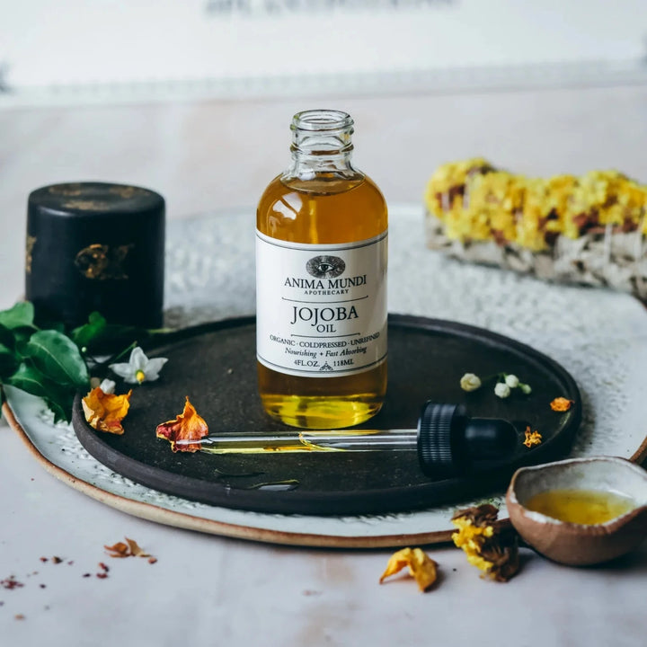 Geöffnete Glasflasche Jojoba Oil von Anima Mundi, Pipette liegend davor.