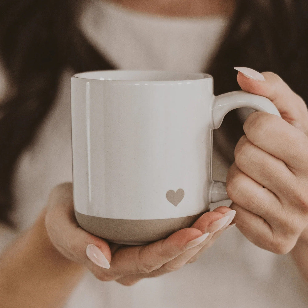 Handgefertigte Herz-Tasse mit gesprenkeltem Design, in zwei Frauenhänden gehalten
