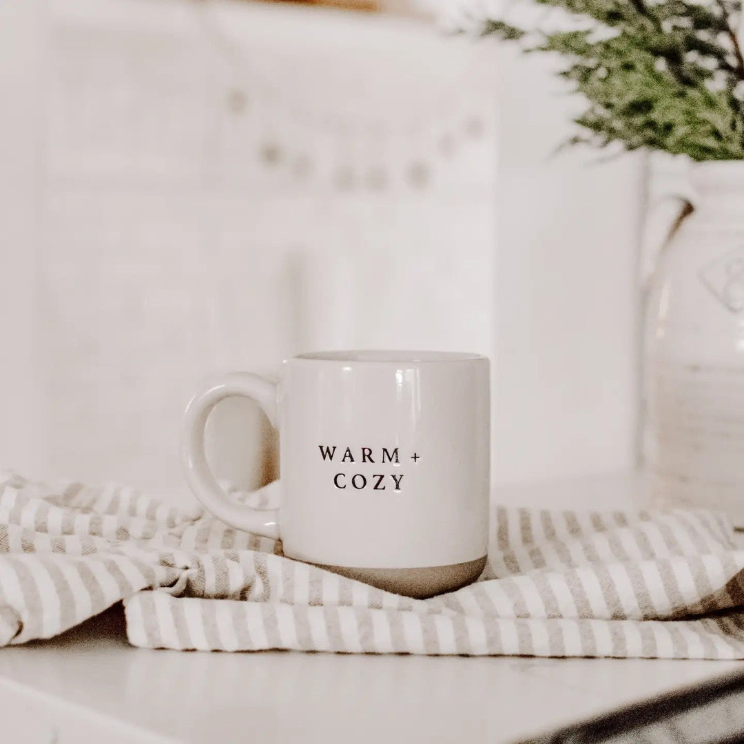 Sweet Water Decor Warm and Cozy Kaffeetasse auf auf Esstisch, daneben eine Decke – gemütliche Szene North Glow